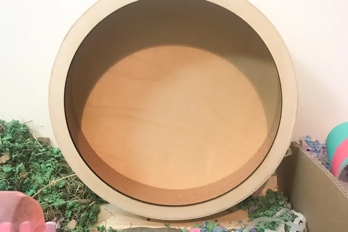 Rueda de madera maciza de 33 cm dentro de una jaula para hámster sirio con sustrato de papel